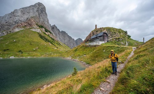 Mountaineer on hiking trail at Wolayersee, Alpine Club hut Wolayerseehütte, rocky cloudy mountains,