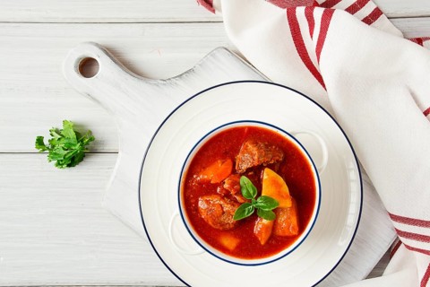 Potatoes stewed with meat, in tomato sauce, with spices and herbs, no people, on a white table