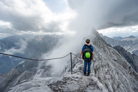 Mountaineer on a narrow rocky ridge on a steel cable, Watzmann crossing to Watzmann Mittelspitze,