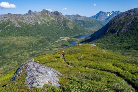 View of mountain landscape and valley with lakes, mountaineer on hiking trail to the summit of
