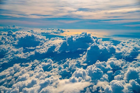 Golden hour sunlight illuminates a vast expanse of fluffy white clouds over coron island,