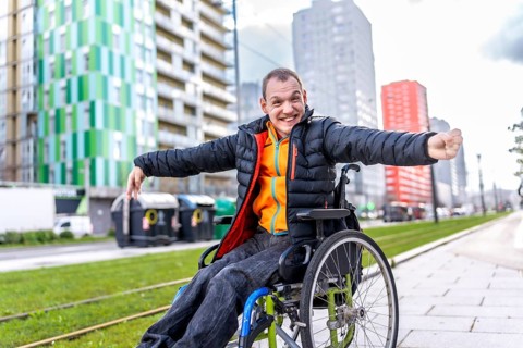 Young disabled man is joyfully navigating the city in his wheelchair, embracing independence and