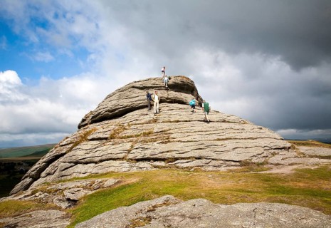 People scrambling on a granite tor near Haytor, Dartmoor national park, Devon, England, United