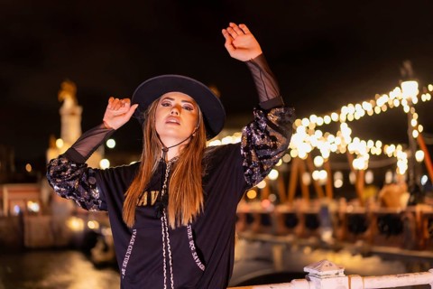 Christmas lights in the city, Caucasian blonde girl dressed in black with a hat on an illuminated
