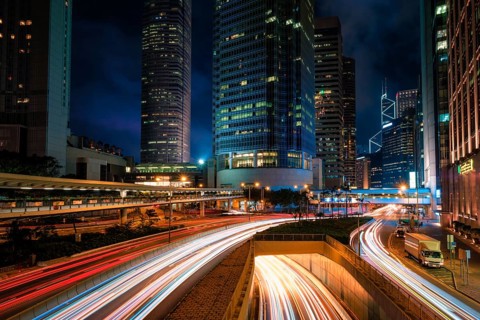 Street traffic in Hong Kong at night. Office skyscraper buildings and busy traffic on highway road