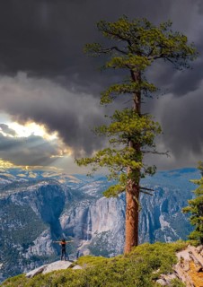 A young woman in Sentinel Dome looking at Upper Yosemite Fall, Yosemite National Park. United