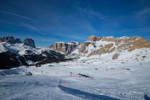 View of a ski resort piste with people skiing in Dolomites in Italy. Ski area Belvedere. Canazei,