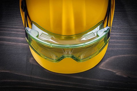 Safety glasses and building helmet on vintage wooden board