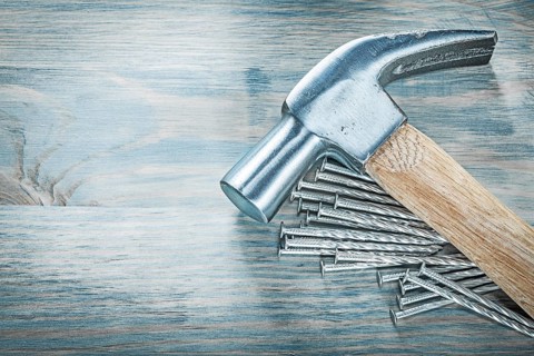 Claw hammer nails on wooden board construction concept