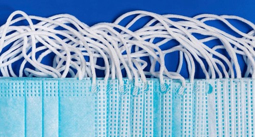 Close-up view of virus protection face mask with rubber ear straps on blue background as protection