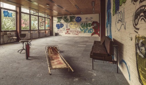 A room in decay with graffiti and damaged furniture, flooded with daylight, Institute of Molecular