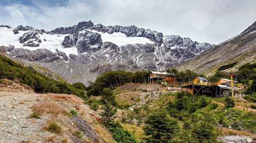 Mountain landscape with snow-covered peak and huts in the foreground on a cloudy day, The landscape