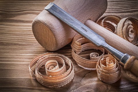 Wooden mallet flat chisels planning chips on vintage wood board construction concept