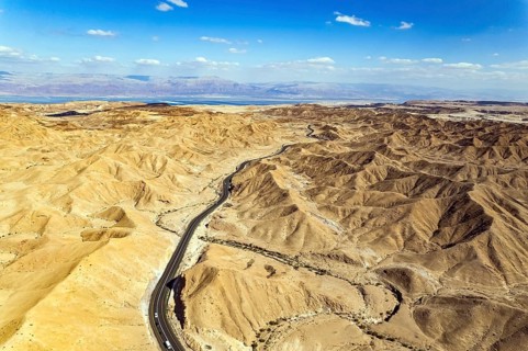Desert on the shores of the Dead Sea. Asphalt highway meanders among the hills. Dead Sea mud has