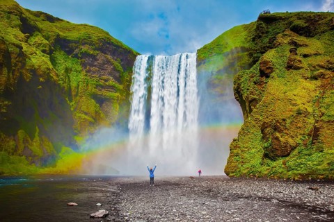 Grand waterfall in Iceland - Skogafoss. Picturesque huge rainbow appears in the water mist.