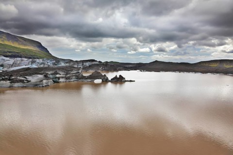 Skaftafell National Park. Ice covered with volcanic ash. Mirror Lake, formed as a result of thawing