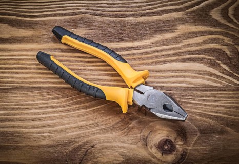 Gripping tongs on vintage wooden board construction concept
