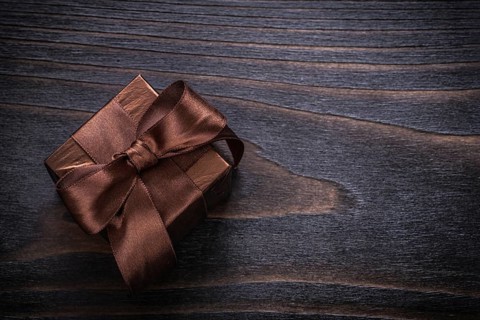 Boxed present with brown bows on vintage wood board