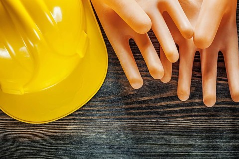 Hard hat insulating gloves on wooden board