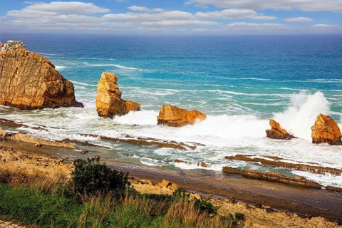 Storm waves break on the coastal rocks. Snow-white sea foam glistens in the dim autumn sun. Playa