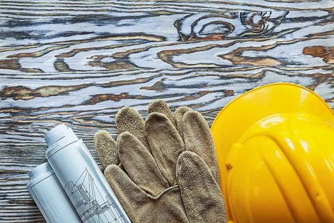 Pair of safety gloves construction plans hard hat on vintage wooden board