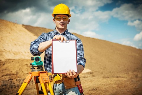 A young worker demonstrating clipboard on construction site