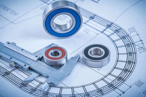 Metal roller bearings and trammel caliper on blueprint construction concept