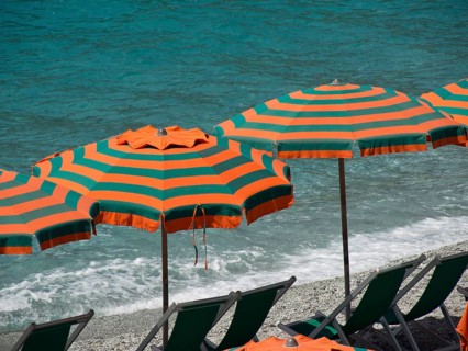 Close-up of orange-green parasols on the sandy seashore, Monte rosso, cinque terre, Italy, Europe