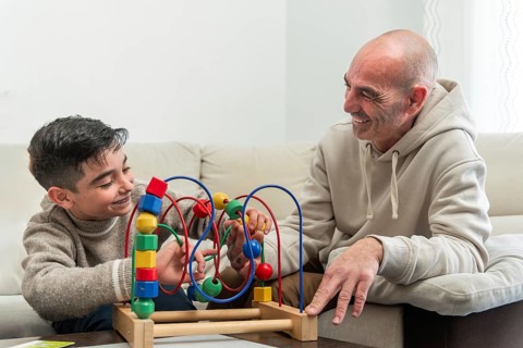 Grandfather and grandson enjoying quality time together, playing with a colorful wooden bead maze
