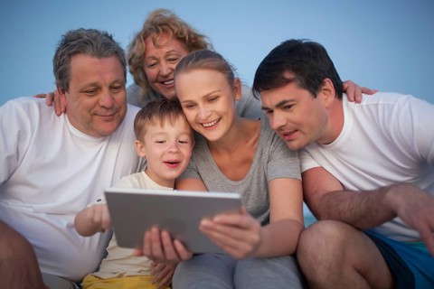 Happy big family having good time together. Grandparents and parents looking at the pad screen