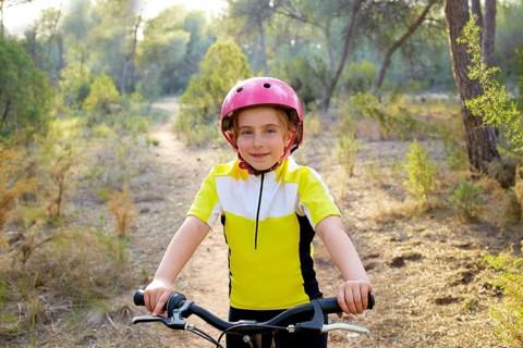 Kid girl biker in mountain bike MTB at mediterranean forest