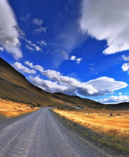 The dirt road in the Chile National Park Torres del Paine. Magic clouds incredible shapes formed by