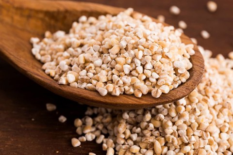 Barley groats on wooden spoon