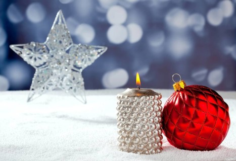 Christmas card of silver star bauble and candle on snow and blue background