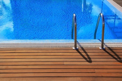 Blue swimming pool with teak wood flooring deck summer vacation concept
