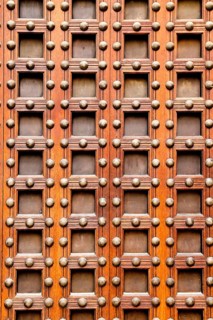 Ancient church castle wooden door with nails and little square shapes in spain