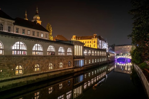 Iconic building of the central market in Ljubljana illuminated at night, the bridge of Preseren