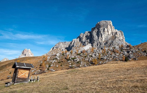 Beautiful mountain landscape with Dolomite rocky peak and a wooden lodge at picturesque Passo Di