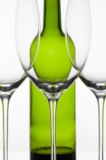 Three empty glasses of wine and green bottle on the white background