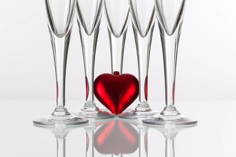 Five champagne glasses and red heart on a glass plate