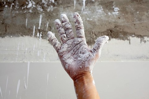 Astist plastering man hand with white dried cracked plaster texture in fingers