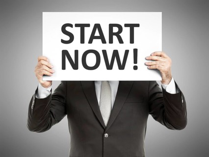 A business man holding a paper in front of his face with the text start now