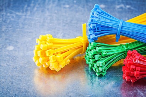 Multicolored plastic zip cable ties on metallic background construction concept