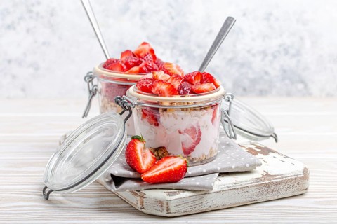 Parfait with Fresh Strawberries, Yoghurt and Crunchy Granola in Transparent Glass Mason Jars on