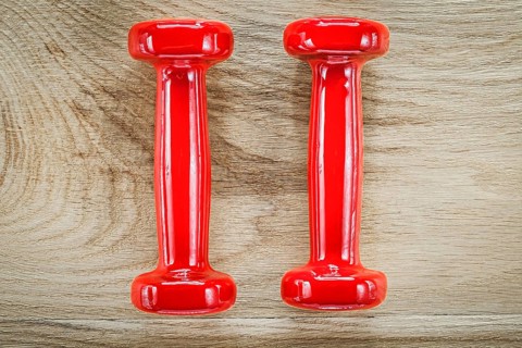 Red dumbbell weights on wooden board fitness concept
