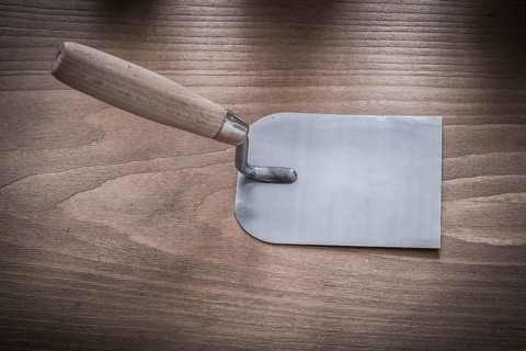 Metal bricklaying trowel on vintage wood board horizontal image