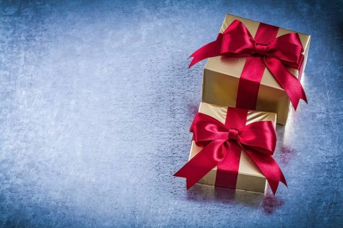 Boxed golden presents with red bow on scratched metallic background