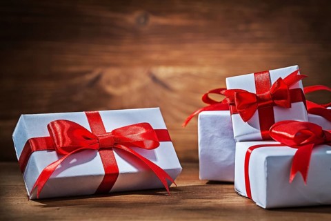 White giftboxes with red ribbons on vintage wood