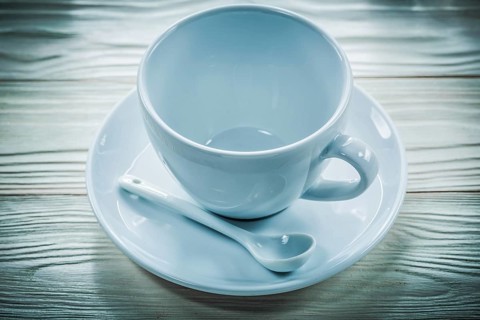 White ceramic cup saucer teaspoon on wooden board