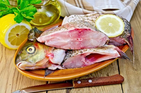 Bream whole peeled and cut into chunks in a clay plate, parsley, lemon, vegetable oil, napkin,